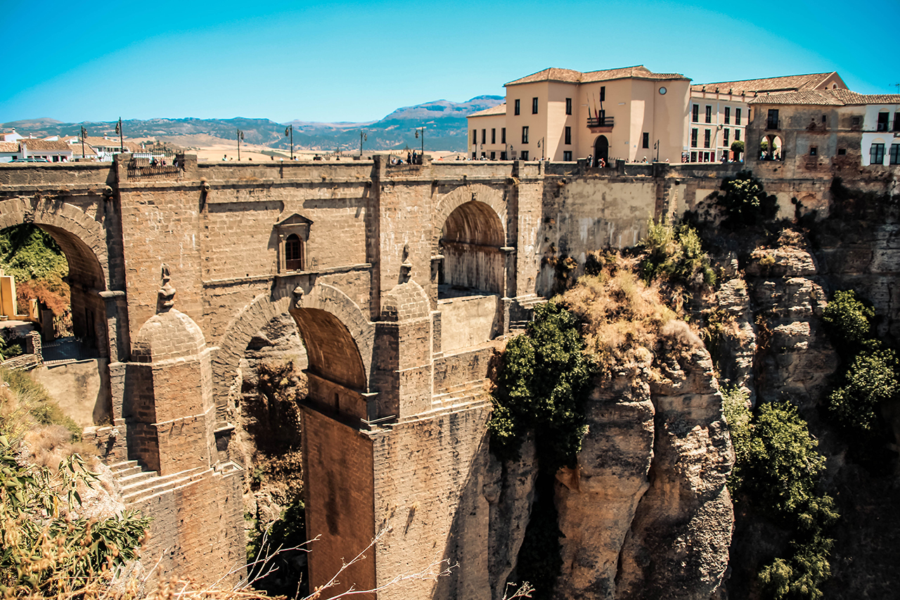Stunning view of Ronda, showcasing its iconic bridge and whitewashed buildings against a backdrop of mountains.